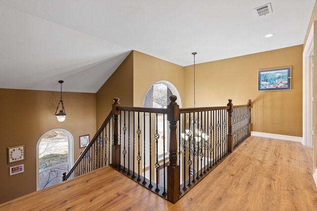 hallway with hardwood / wood-style flooring and vaulted ceiling