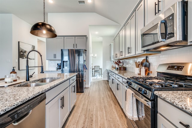 kitchen featuring pendant lighting, gray cabinetry, sink, vaulted ceiling, and stainless steel appliances