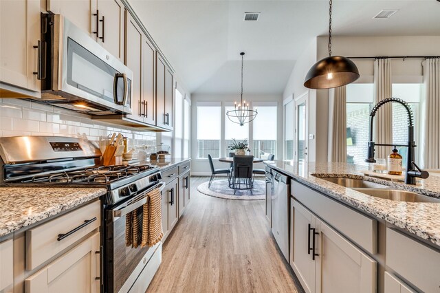 kitchen with pendant lighting, a notable chandelier, sink, and appliances with stainless steel finishes