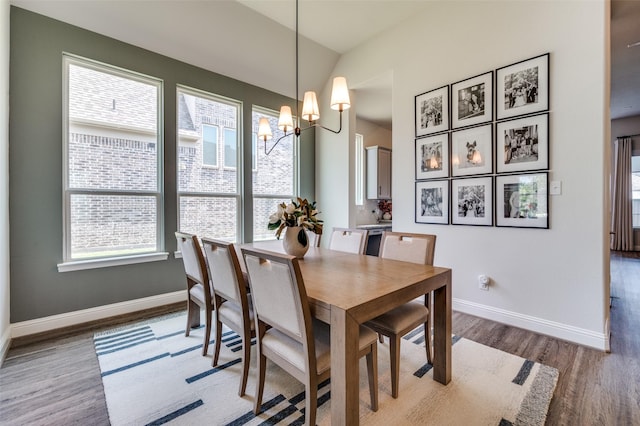 dining room featuring vaulted ceiling, light hardwood / wood-style flooring, and an inviting chandelier