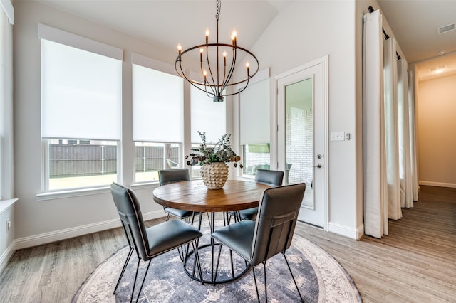 dining room with a notable chandelier, light hardwood / wood-style floors, and lofted ceiling