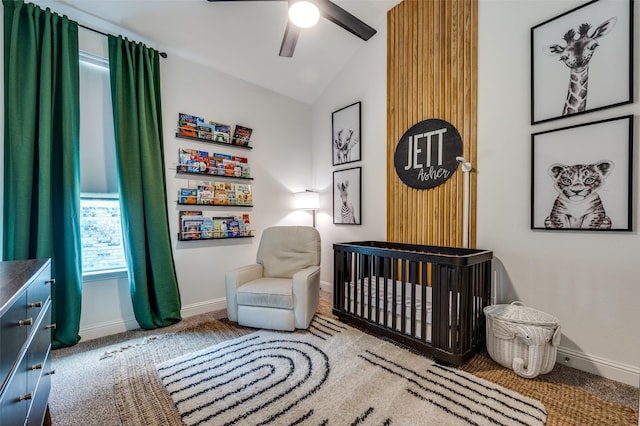 carpeted bedroom with ceiling fan, a crib, and vaulted ceiling