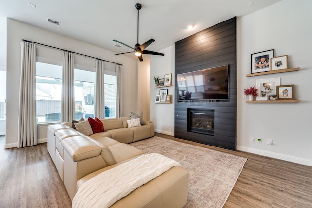 living room featuring ceiling fan, a fireplace, and wood-type flooring