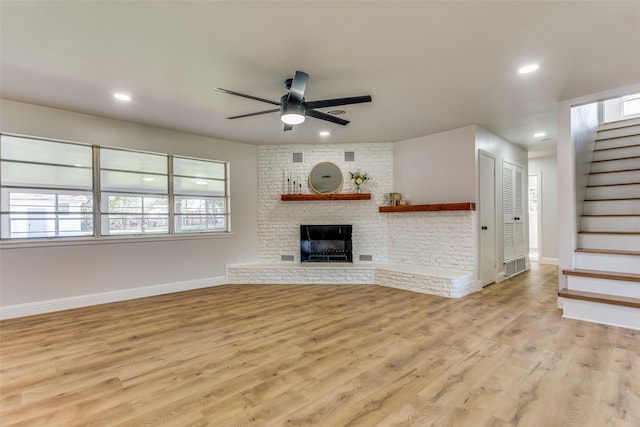 unfurnished living room with ceiling fan, a fireplace, and light hardwood / wood-style floors