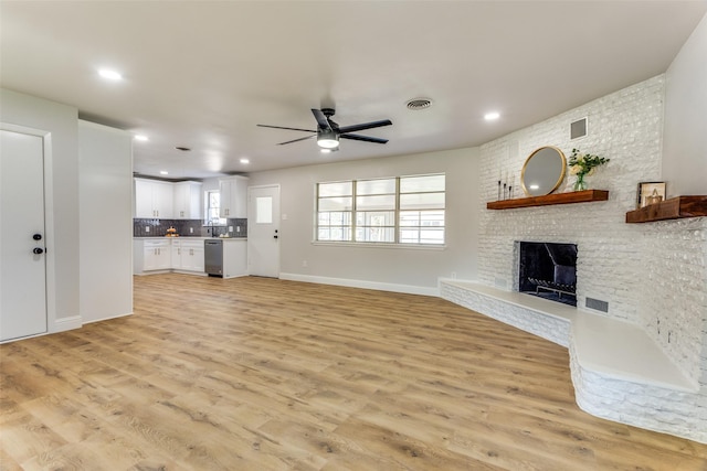 unfurnished living room with a fireplace, ceiling fan, and light wood-type flooring