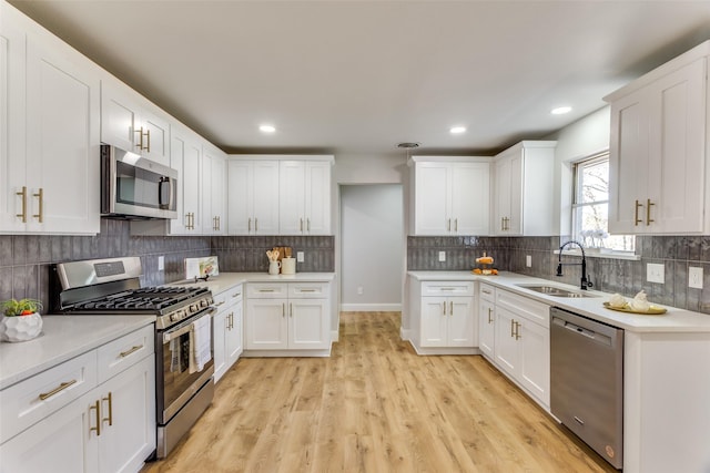 kitchen with white cabinetry, appliances with stainless steel finishes, sink, and decorative backsplash