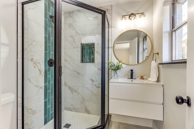 bathroom featuring a shower with door, vanity, and toilet