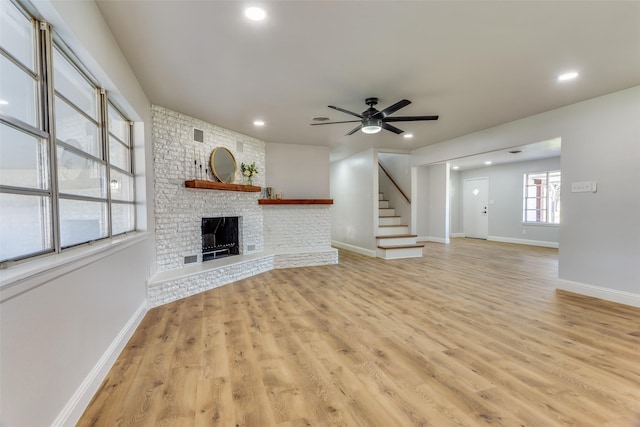 unfurnished living room featuring ceiling fan, a fireplace, and light hardwood / wood-style flooring