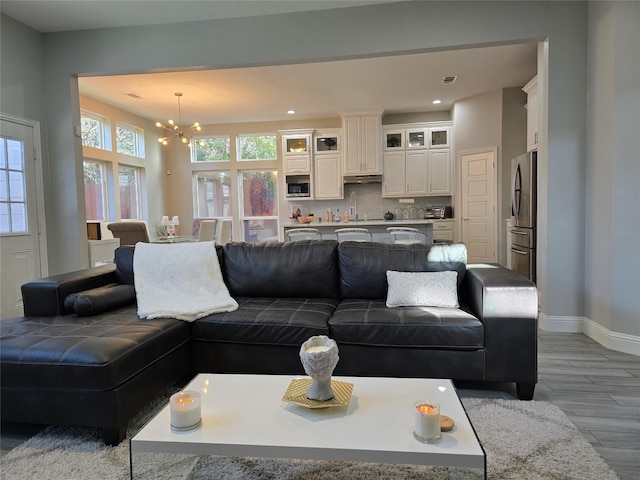 living room featuring sink, light hardwood / wood-style flooring, and a notable chandelier