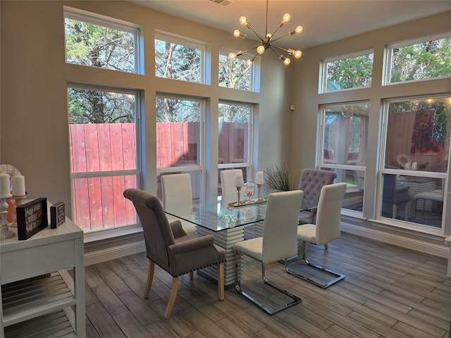 dining space featuring hardwood / wood-style flooring, a healthy amount of sunlight, a high ceiling, and an inviting chandelier