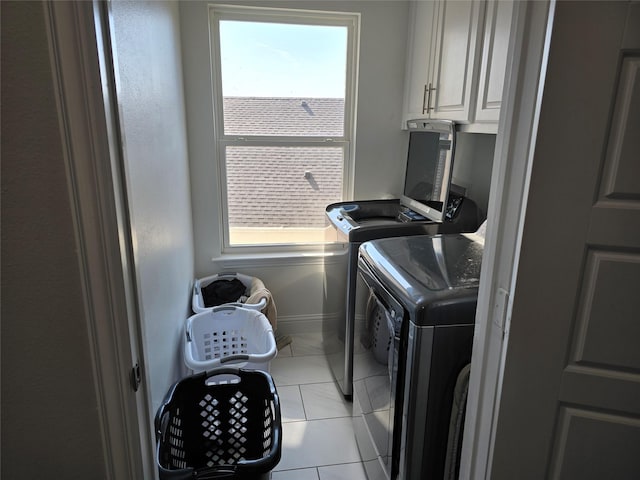 clothes washing area with cabinets, independent washer and dryer, and light tile patterned flooring