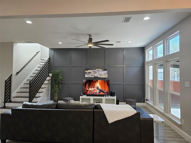 living room with light hardwood / wood-style floors, a large fireplace, and ceiling fan