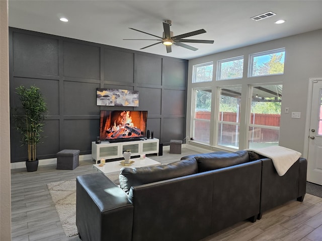 living room featuring ceiling fan, light wood-type flooring, and a fireplace