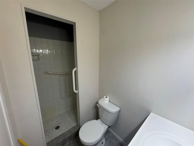 bathroom featuring a tile shower, tile patterned floors, sink, and toilet