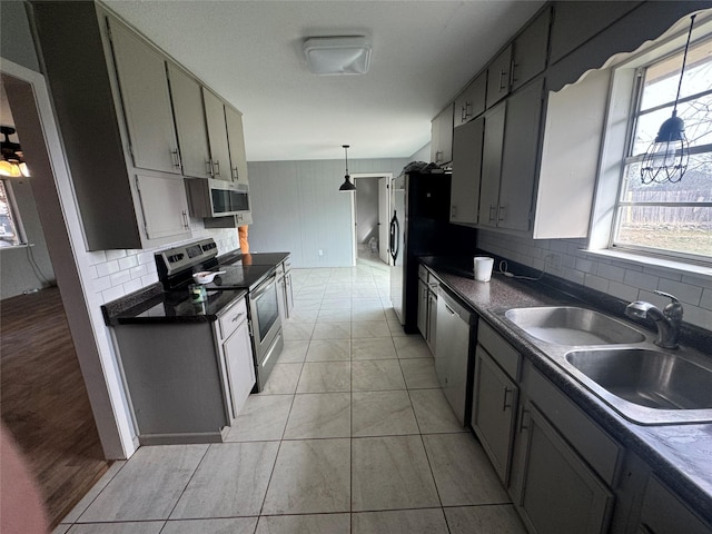 kitchen featuring gray cabinetry, stainless steel appliances, sink, light tile patterned floors, and decorative light fixtures