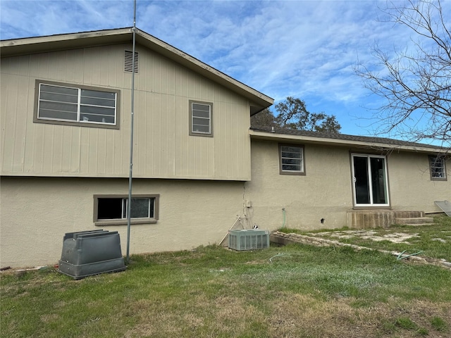 back of property with a lawn and central AC