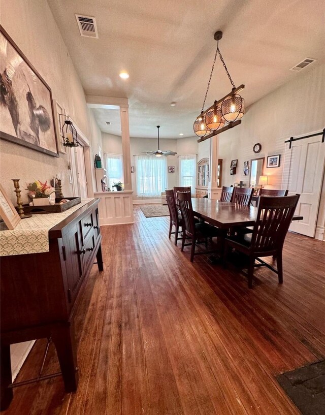 dining room with dark hardwood / wood-style floors, ceiling fan, a barn door, and a textured ceiling