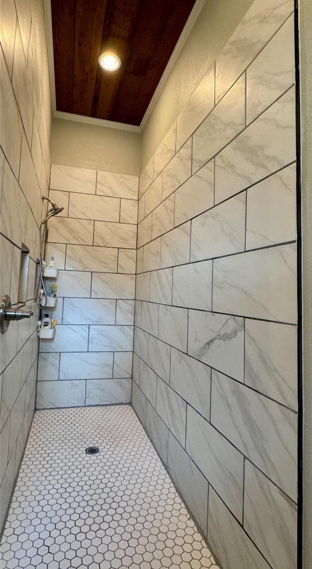 bathroom with a tile shower and ornamental molding