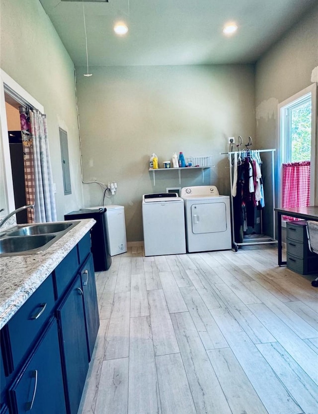 laundry room with sink, washer and clothes dryer, electric panel, cabinets, and light hardwood / wood-style floors