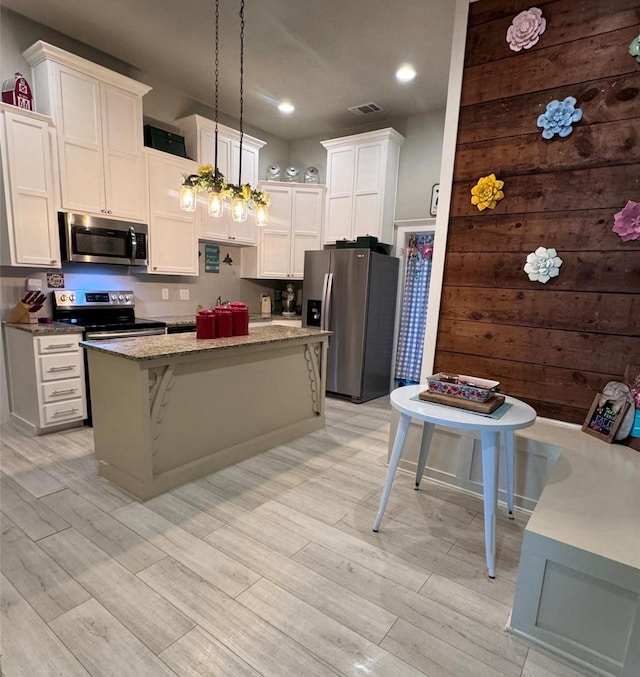 kitchen with pendant lighting, a breakfast bar area, stainless steel appliances, white cabinets, and a kitchen island