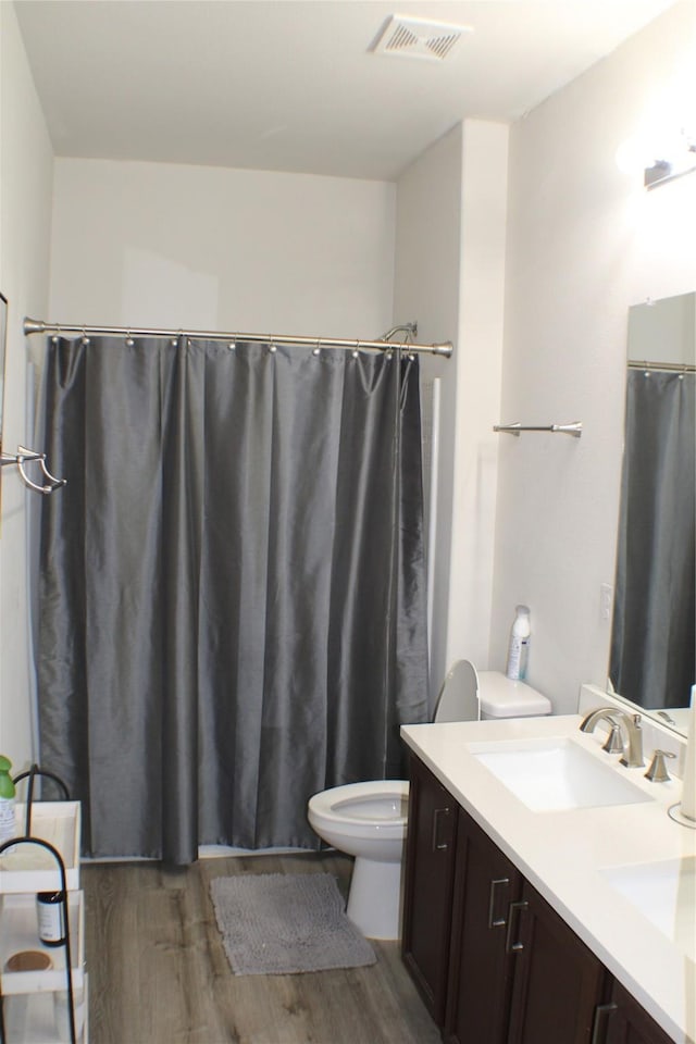 bathroom with walk in shower, wood-type flooring, toilet, and vanity