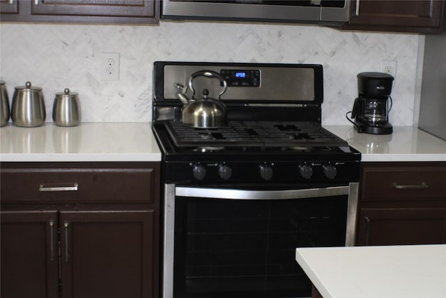 kitchen featuring dark brown cabinetry, decorative backsplash, and stainless steel gas range