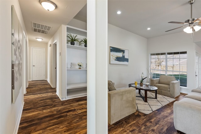 living room featuring ceiling fan, dark wood-type flooring, and built in shelves