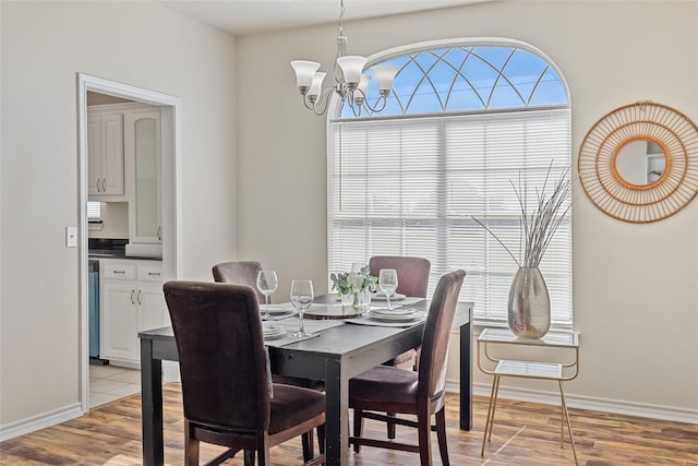 dining area with light hardwood / wood-style flooring and a notable chandelier