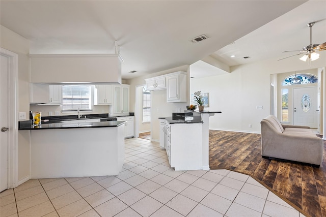 kitchen with light tile patterned flooring, white cabinetry, and kitchen peninsula