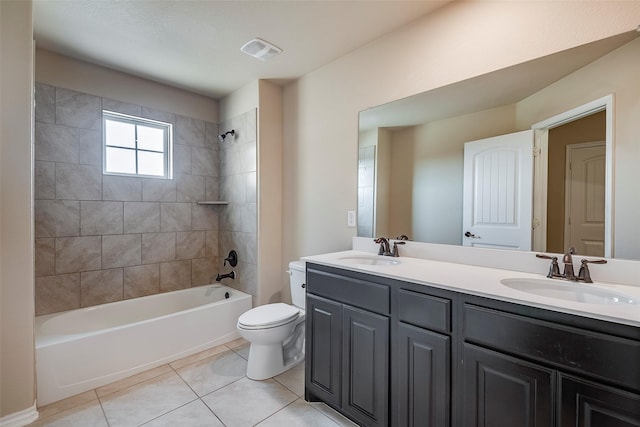 full bathroom with tile patterned flooring, tiled shower / bath, vanity, and toilet