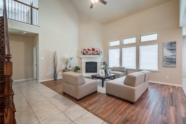 tiled living room with ceiling fan and a high ceiling