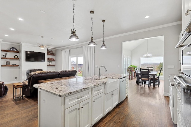 kitchen featuring a fireplace, sink, an island with sink, and decorative light fixtures