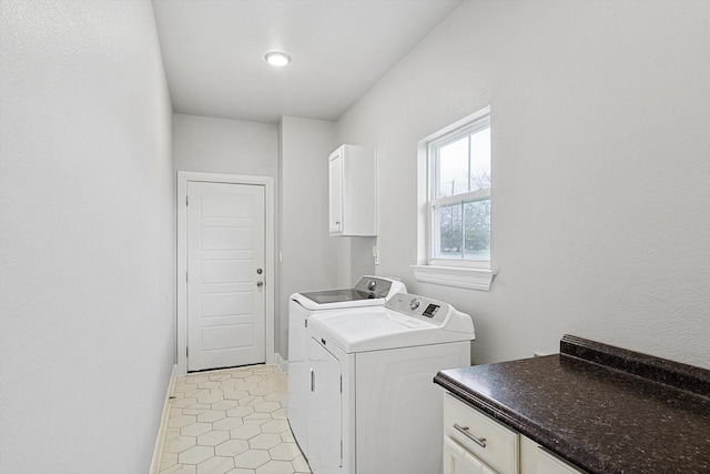 clothes washing area featuring washer and clothes dryer, cabinets, and light tile patterned floors