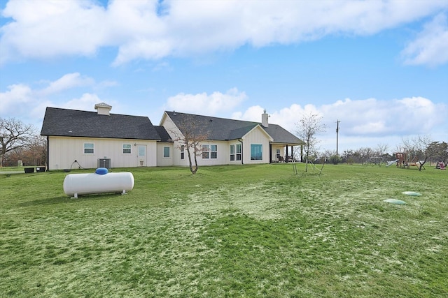 rear view of house with cooling unit and a lawn