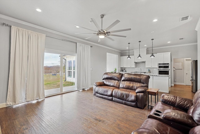 living room featuring ceiling fan, ornamental molding, sink, and light hardwood / wood-style flooring