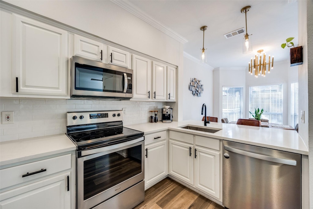 kitchen featuring hanging light fixtures, sink, white cabinets, and stainless steel appliances