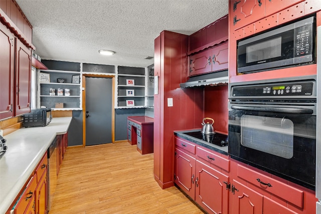 kitchen with light wood-type flooring, a textured ceiling, built in features, and black appliances