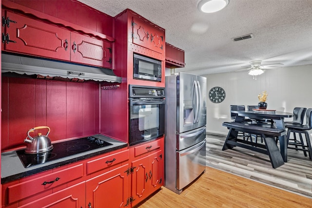 kitchen with appliances with stainless steel finishes, a textured ceiling, light hardwood / wood-style flooring, and ceiling fan