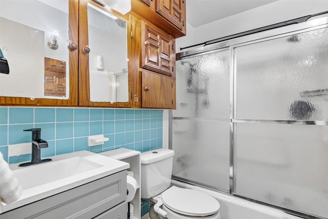 full bathroom with tasteful backsplash, vanity, shower / bath combination with glass door, tile walls, and toilet