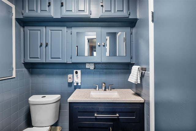 bathroom featuring vanity, tile walls, and toilet