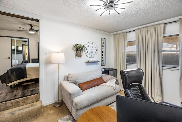 living room with a textured ceiling, light colored carpet, and ceiling fan