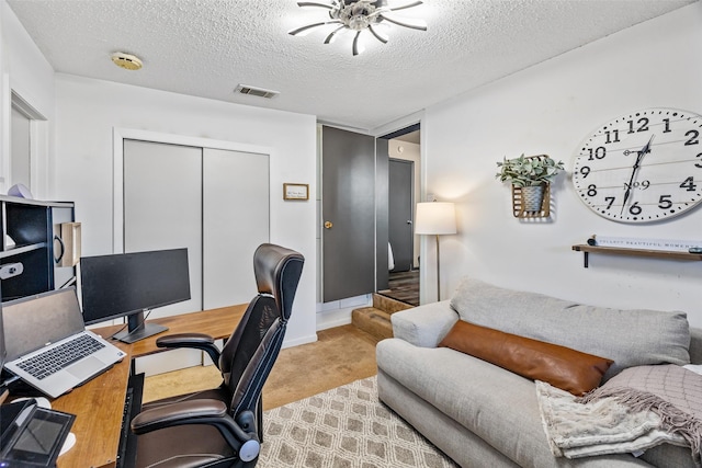 carpeted home office featuring a textured ceiling