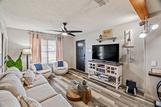 living room featuring ceiling fan, beamed ceiling, a textured ceiling, and hardwood / wood-style flooring