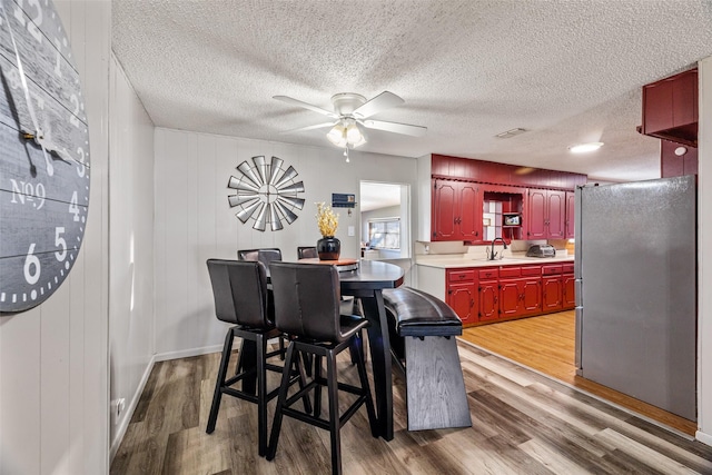 dining area with a textured ceiling, ceiling fan, light hardwood / wood-style floors, and sink