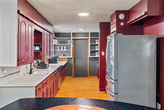 kitchen with stainless steel fridge, sink, a textured ceiling, and light hardwood / wood-style flooring