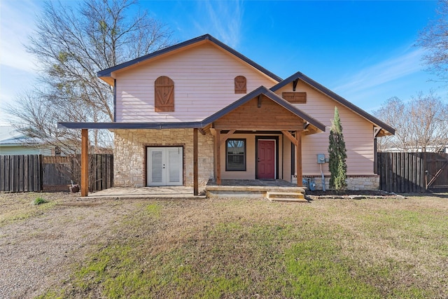 view of front of property featuring stone siding, a gate, fence, and a front yard