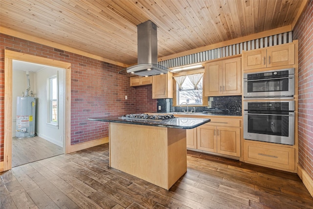 kitchen with water heater, appliances with stainless steel finishes, island range hood, a kitchen island, and light brown cabinetry