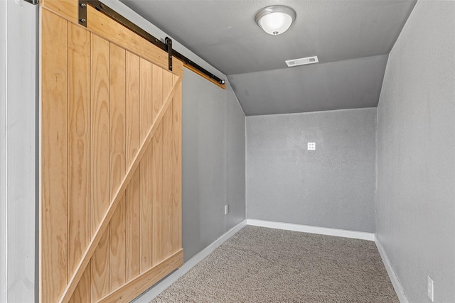 interior space with carpet floors, a barn door, visible vents, and baseboards