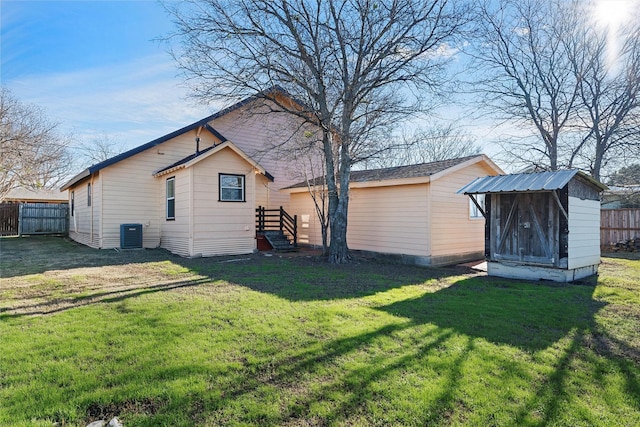 rear view of house featuring central AC, a lawn, and a storage unit