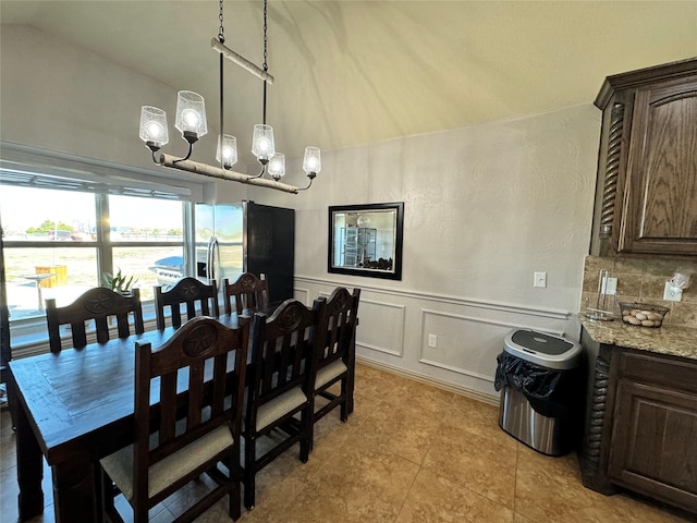 tiled dining space featuring lofted ceiling and a chandelier